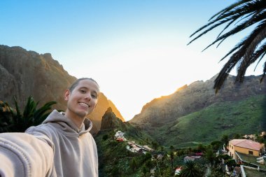 Adamın biri Masca Vadisi, Tenerife 'deki görkemli bir dağın önünde selfie çekiyor..