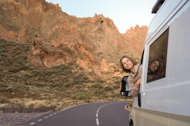 Genç adam yol kenarına park etmiş bir minibüsün camından dışarı doğru eğildi..