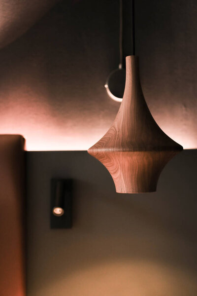 A wooden light fixture suspended from the ceiling of a hotel room, providing illumination and style.