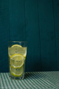 Güzel bir arka planda taze limon dilimleri ile şeffaf bir bardak limonata.