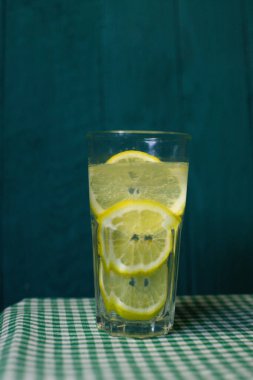 Güzel bir arka planda taze limon dilimleri ile şeffaf bir bardak limonata.