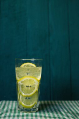 Güzel bir arka planda taze limon dilimleri ile şeffaf bir bardak limonata.