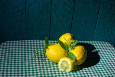 Sulu taze limonlar ve yapraklar güzel mavi bir arka planda damalı bir kumaşa serilmiş.