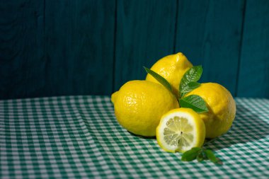 Yeşil yapraklı taze limonlar ve kareli masa örtüsü