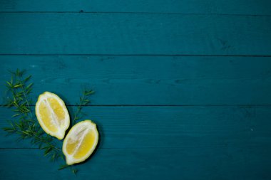 İki sulu, taze limon hasırı ve ahşap desenli mavi arka planda yeşillik filizleri.