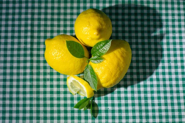 新鲜柠檬 绿叶放在格子桌布上 — 图库照片