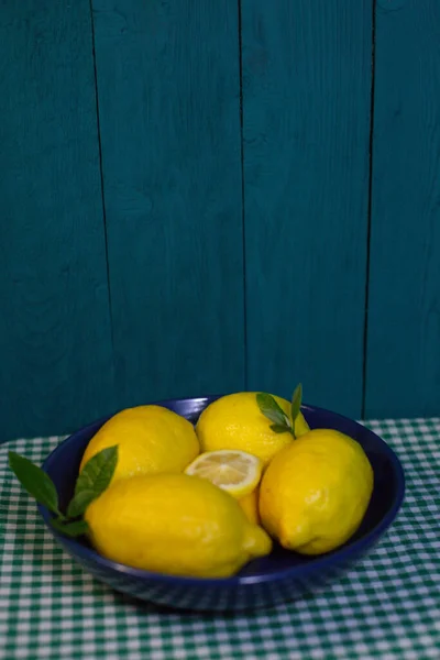 Frische Zitronen Mit Blättern Einer Dunkelblauen Schüssel Auf Einer Karierten — Stockfoto