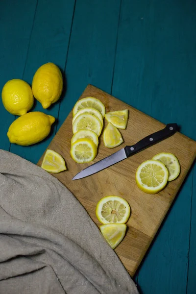 fresh lemons cut into slices on a wooden board with a knife and burlap