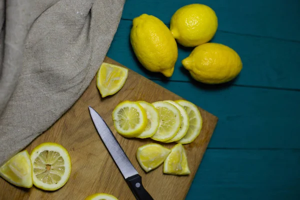 fresh lemons cut into slices on a wooden board with a knife and burlap