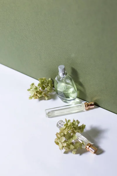 Parfümflaschen Aus Glas Mit Hortensienzweigen Auf Hellem Hintergrund — Stockfoto