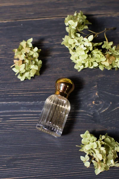 Glasparfümflasche Mit Hortensienzweigen Auf Dunklem Hintergrund Mit Holzstruktur — Stockfoto