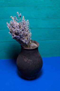 Mavi arka planda lavanta çiçekli siyah sürahi.