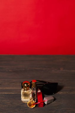 Kırmızı ve siyah arkaplanda kadın aksesuarları, ruj, gözlük, parfüm