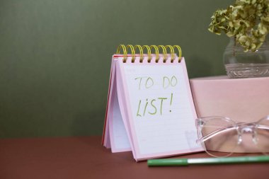 Masada gözlük, kalem ve filizli defter var.