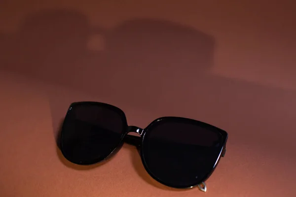 Czarne Okulary Przeciwsłoneczne Grubych Ramkach Pięknym Tle Cieniem Liści — Zdjęcie stockowe