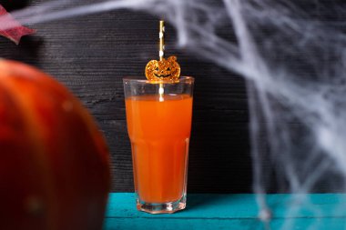 Cadılar Bayramı için bir bardak meyve suyu, balkabağı ve örümcek ağı.