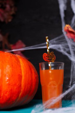 Cadılar Bayramı için bir bardak meyve suyu, balkabağı ve örümcek ağı.