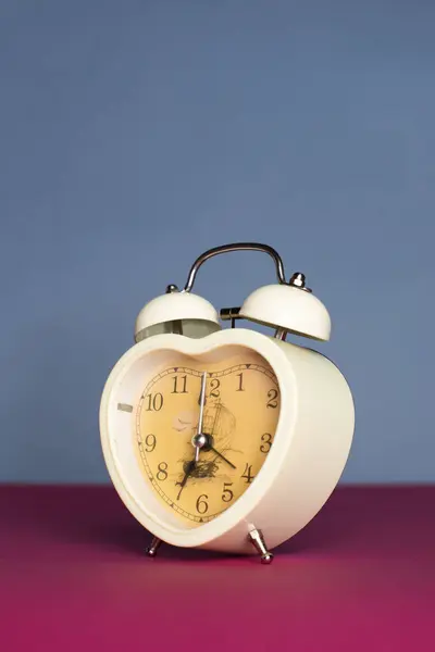 Alarm clock in the shape of a heart on a beautiful background