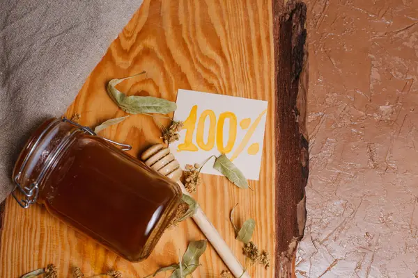 Arkaplanda kuru ıhlamur yaprakları olan bir kavanoz bal.