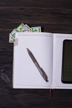 Hesap makinesi ve koyu arkaplanda bir kalem olan bir defter..