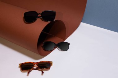 Güneş gözlüğü, beyaz üzerine mavi ve kahverengi arka planlı gözlük.