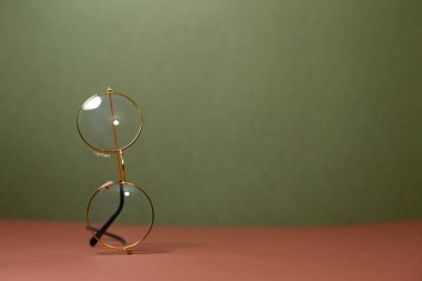 Gözlük, altın çerçeveli gözlük, yazı için yeri olan yeşil bir arka plan.