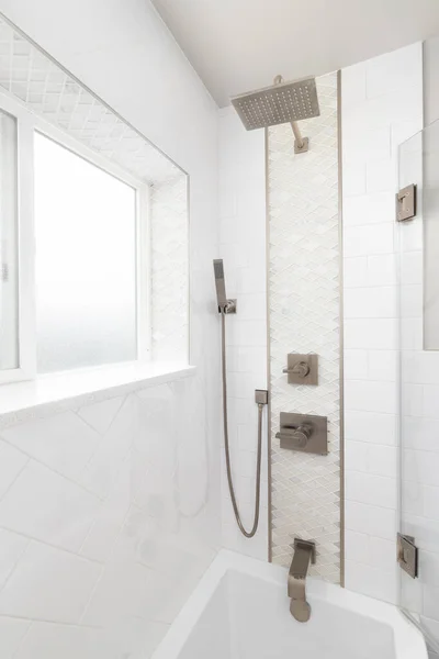 A beautifully renovated shower with herringbone and diamond shaped tiles and bronze faucet.