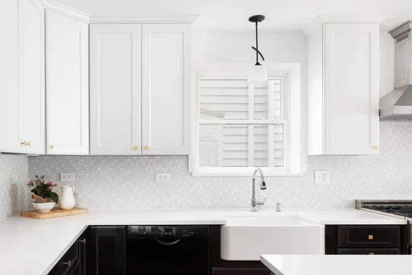 A kitchen detail with white and wood cabinets, a white apron sink, and tiled backsplash.