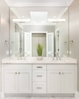 A modern bathroom with a white cabinet, a marble countertop, and lights mounted on the mirror.