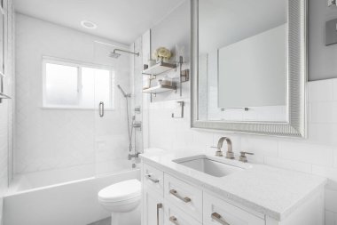 Beyaz makyaj dolabı olan bir banyo, granit tezgah ve büyük ringa kemiği fayanslarıyla kaplı bir duş..