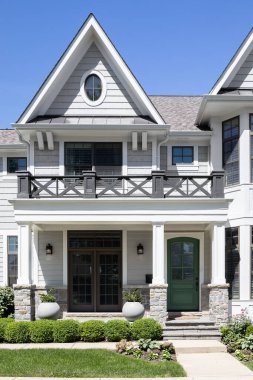 Lüks beyaz ve gri modern bir çiftlik evi girişi ön verandası ve yeşil ön kapısı var. İşaret veya etiket yok.