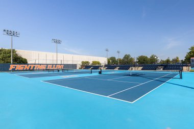 Champaign, IL, USA - September 18, 2024: Tennis Courts at the University of Illinois. The courts are themed with orange and blue with Fighting Illini signs around the fence. clipart