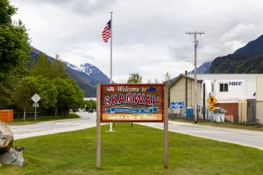 Skagway, AK, ABD - 2 Haziran 2025: Konuklar şehre girerken Skagway tabelasına hoş geldiniz. Burası Alaska seyahati yapan konuklar için popüler bir gemi limanı..