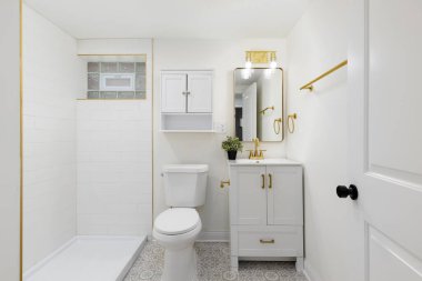 Döşemesi desenli bir banyo, altın musluğu ve donanımlı beyaz dolap ve duş beyazı metro fayanslı duş..