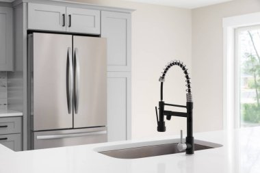 Mutfak musluğu, siyah ve paslanmaz çelik musluk, beyaz mermer tezgah ve gri dolaplar..