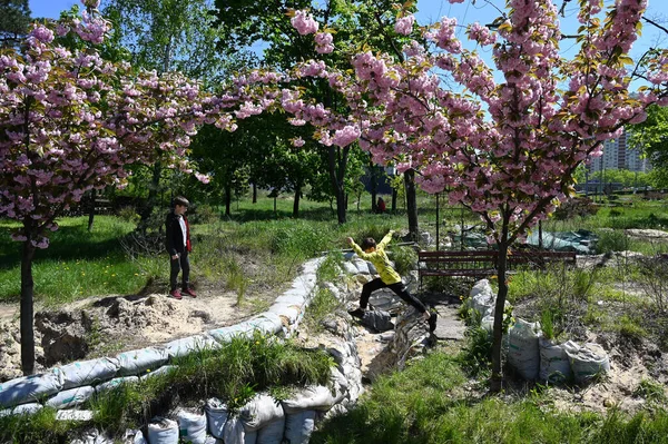 stock image Kyiv, Ukraine - May 6, 2023: Two boys play in the trenches that were built in a sakura park on the outskirts of Kyiv due to Russian aggression