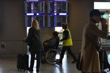 Varşova, Polonya - 17 Ekim 2023: Bir terminal çalışanı tekerlekli sandalyedeki bir yolcunun uçuş programına bakmasına yardım ediyor. Varşova Chopin Havaalanı. Seyahat kavramı