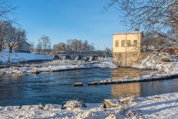 Winter view of water flushing from an open gate at a hydro electric power plant in Sweden, on a bright winter day with blue sky and sunlight
