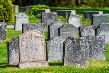 İsveç 'teki bir mezarlıkta gün ışığında eskimiş ve isimsiz mezar taşları grubu.