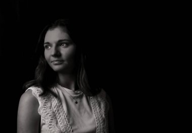 Black and white portrait of a young woman on black background