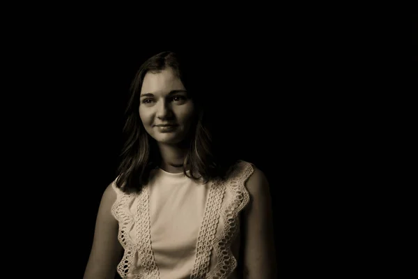 Black and white portrait of a young woman on black background