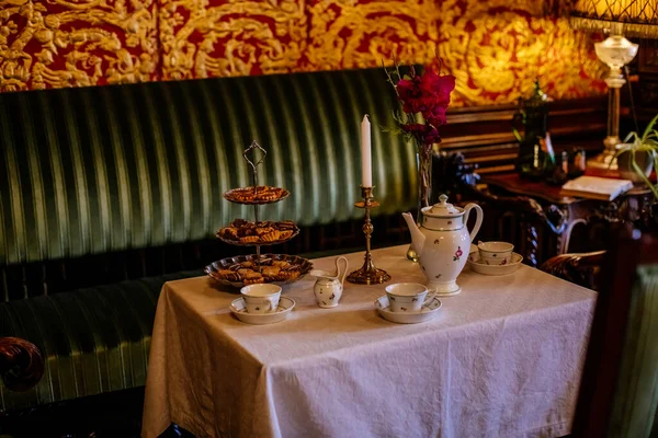 stock image Hradek u nechanic, Czech Republic, 8 October 2022:  Castle or chateau interior with wooden carved furniture, guest room with leather gilded Belgian wallpaper, tea set on table, glass vintage decanter