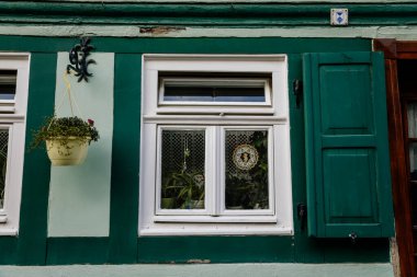 Quedlinburg, Saxony-Anhalt, Germany, 28 October 2022: Antique window with wooden frame, house in medieval town, Typical beautiful streets of ancient city, half-timbered home, white and green shutters