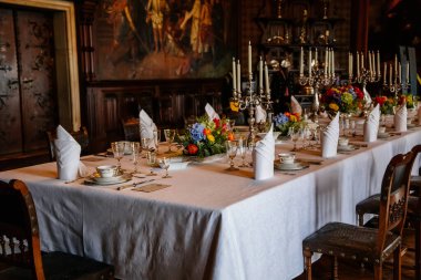 Wernigerode, Saxony-Anhalt, Germany, 29 October 2022:  representative chateau or castle interiors, dining room with long table and gilded porcelain dishes, plates and glasses, golden candelabra