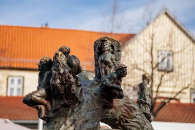 Wernigerode, Saxony-Anhalt, Germany, 29 October 2022:  Water fountain in the form of ball with tree trunk and sculptures sitting on it, Modern sculpture on streets of city, vintage timber frame houses