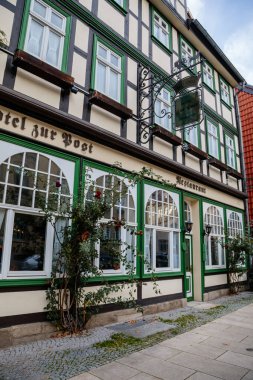Wernigerode, Saxony-Anhalt, Germany, 29 October 2022: Historic old vintage colored timber frame houses in medieval town, UNESCO World Heritage city, half-timbered home at sunny autumn day, cobblestone