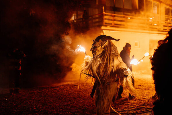 Trutnov, Czech Republic, 17 December 2022: Traditional show Zazij Krampus, parade of masks demonic creatures, devil in flames at winter night, Christmas holidays, fantasy handmade wooden masks