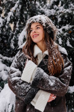 Kış tatili seyahati, Noel günü, yeni yıl, karlı ormanda güzel mutlu kadın portresi, doğa ormanı, kayak merkezi, eğlence aktivitesi, ladin dallarından düşen kardan hoşlanan genç bayan.