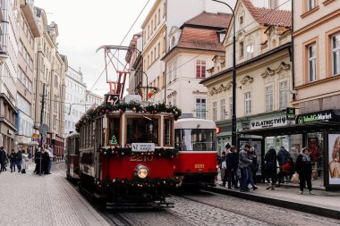 Prag, Çek Cumhuriyeti, 16 Aralık 2023: Çelenk ve ağaçlarla süslenmiş Noel Tramvayı, tarihi merkez caddesinde peri ışıkları, yeni yıl aydınlatmalı tramvay
