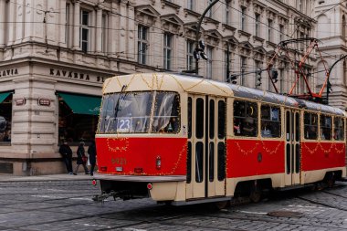 Prag, Çek Cumhuriyeti, 16 Aralık 2023: Çelenk ve ağaçlarla süslenmiş Noel Tramvayı, tarihi merkez caddesinde peri ışıkları, yeni yıl aydınlatmalı tramvay